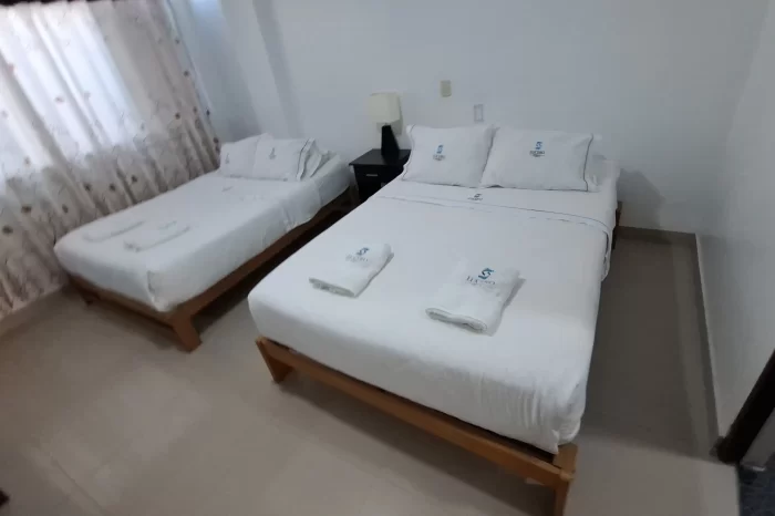 Habitación doble del hotel lucero en paracas con camas dobles con toallas en la cama y las comodidades que deben tener en la habitación.