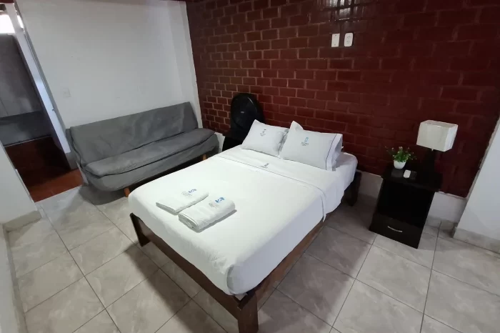 Villa del hotel lucero en paracas con una cama matrimonial y un sofa con un diseño rustico